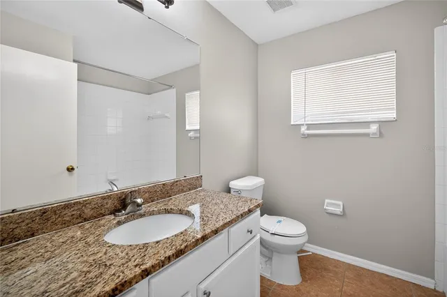 a bathroom with a granite countertop toilet a sink and a mirror