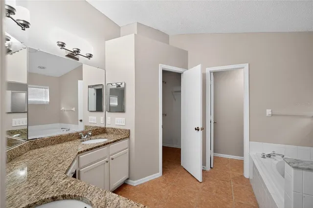 a spacious bathroom with a granite countertop sink and a mirror