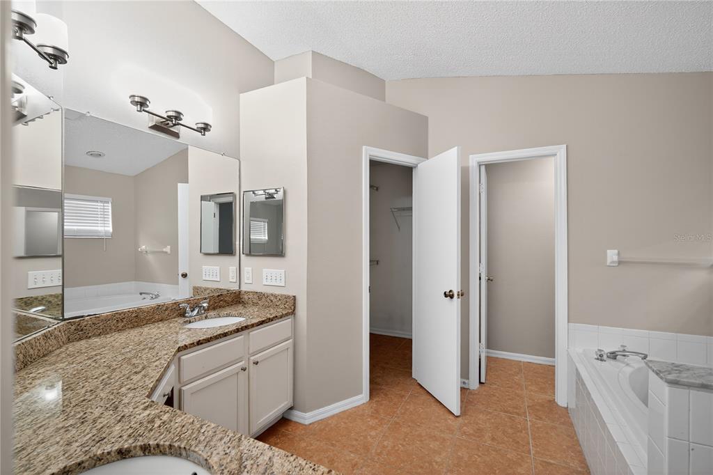 12630 Early Run Lane Riverview, FL 33578 - Photo 23 of 32 a spacious bathroom with a granite countertop sink and a mirror