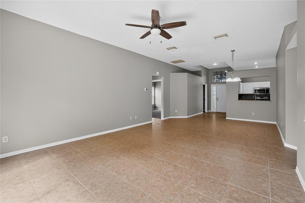 12630 Early Run Lane Riverview, FL 33578 - Photo 4 of 32 an empty room with a ceiling fan and kitchen view