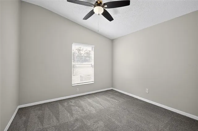 an empty room with a window and a fan