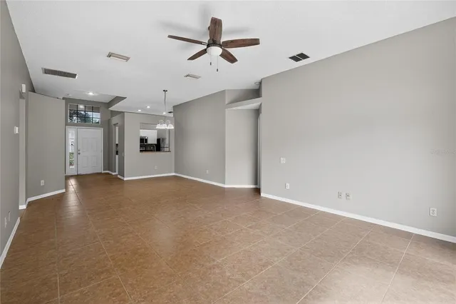 an empty room with chandelier fan and windows
