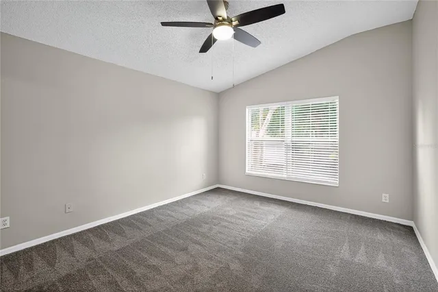 an empty room with ceiling fan and windows