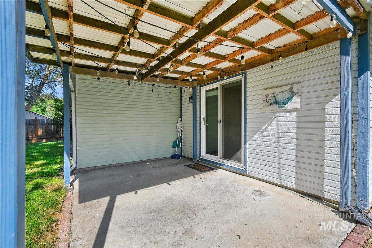 9215 West Preece Street Boise, ID 83704 - Photo 18 of 22 Covered concrete patio featuring a corrugated metal roof, exposed wood beam supports, and string lighting