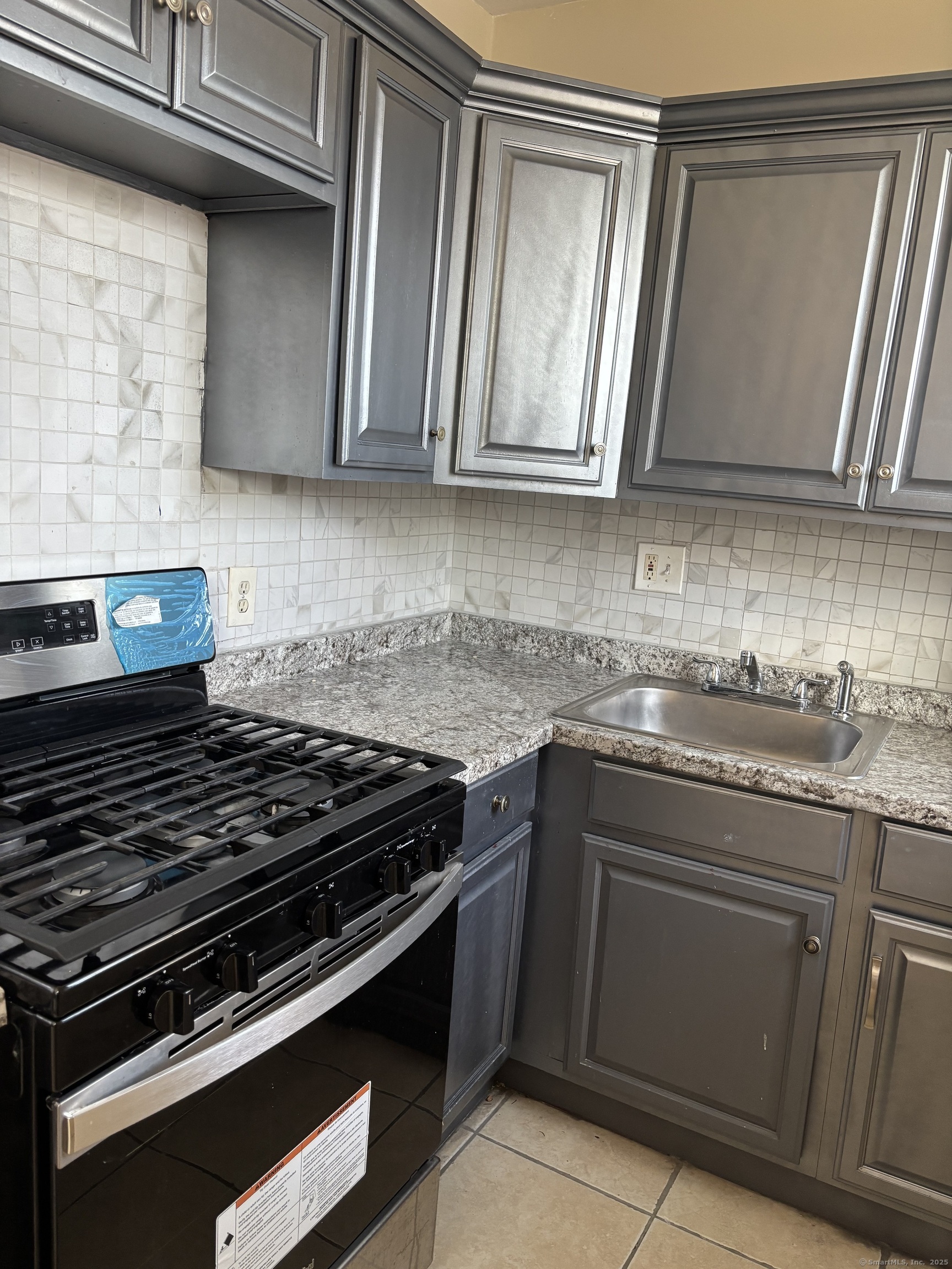 141 Pixlee Place Bridgeport, CT 06610 - Photo 3 of 7 a kitchen with granite countertop stainless steel appliances and white cabinets