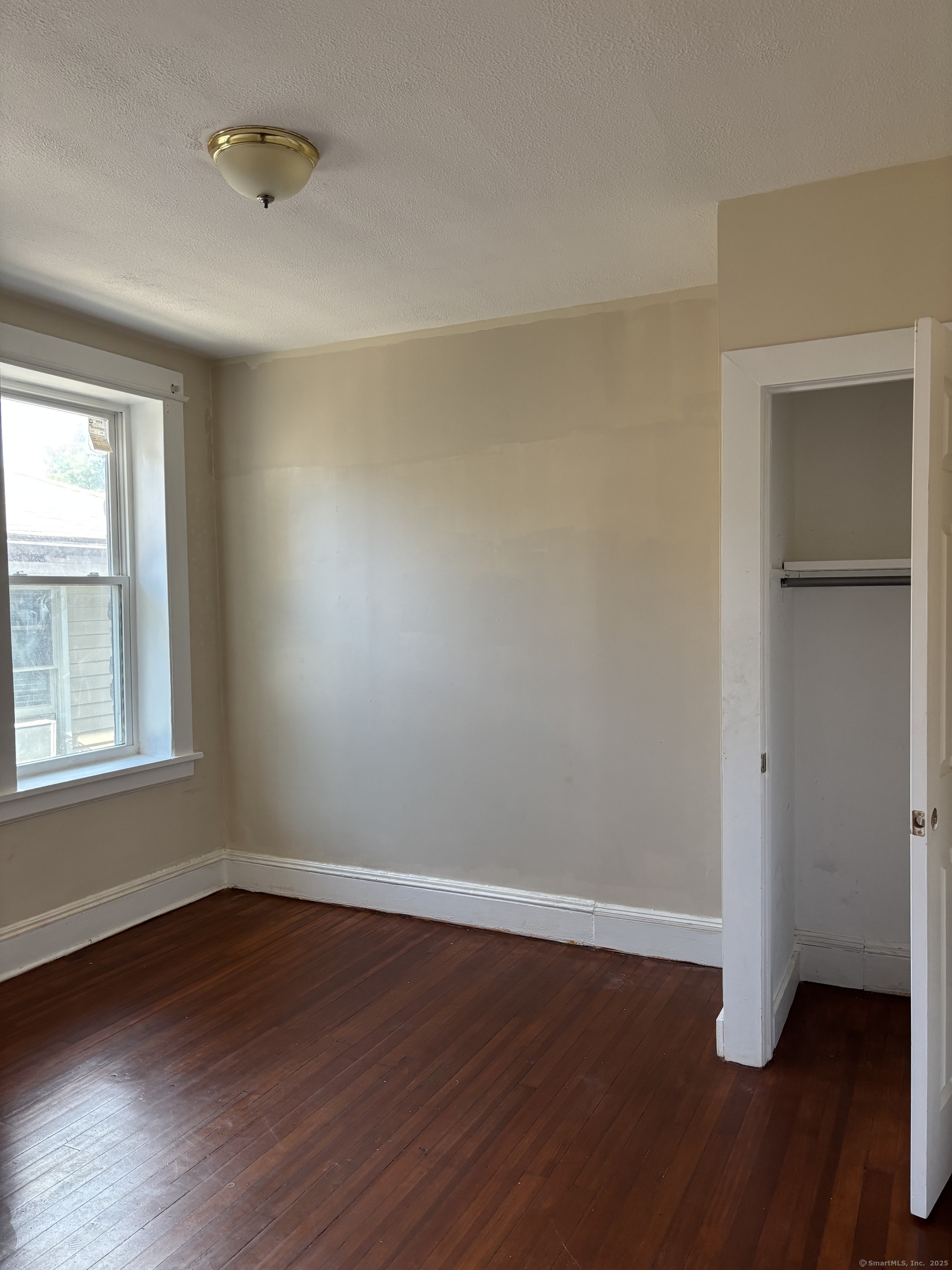 141 Pixlee Place Bridgeport, CT 06610 - Photo 6 of 7 an empty room with wooden floor and windows