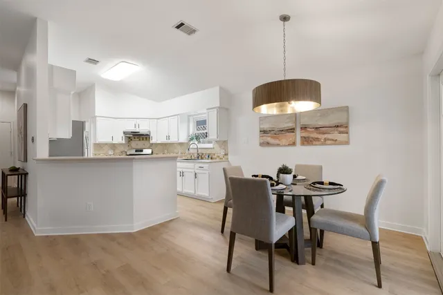 a kitchen with stainless steel appliances kitchen island granite countertop a sink a stove a table and chairs