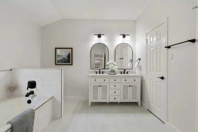 a bathroom with a double vanity sink mirror and bathtub