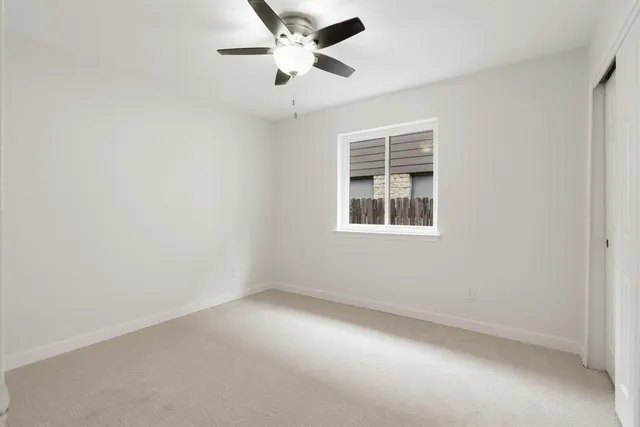 an empty room with a window and a fan