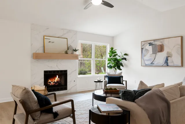 a living room with furniture a fireplace and a large window