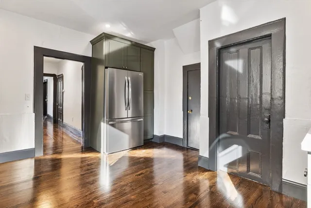 a view of a refrigerator in kitchen and livingroom with wooden floor
