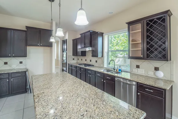 a kitchen with stainless steel appliances kitchen island granite countertop a sink stove and cabinets