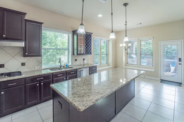 a kitchen with stainless steel appliances granite countertop a sink a counter space and a window