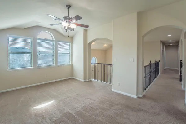 an empty room with chandelier fan and windows