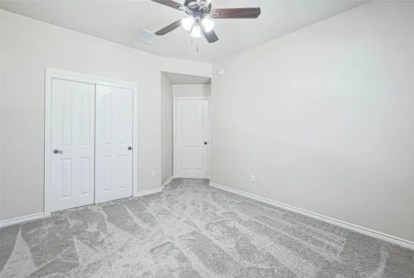 an empty room with chandelier fan and windows