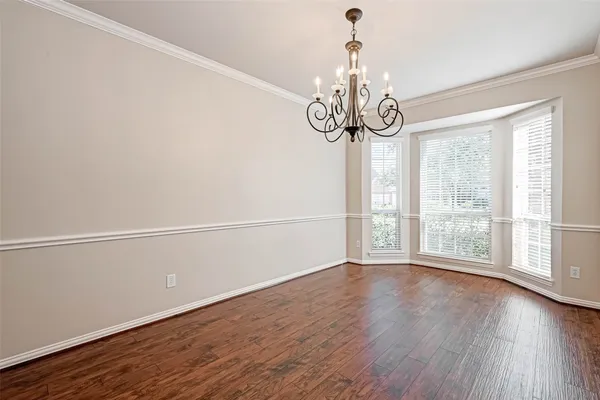 a view of an empty room with wooden floor and windows