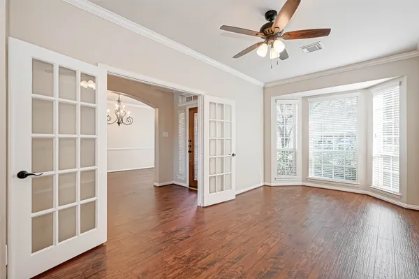 a view of an empty room with wooden floor and a window