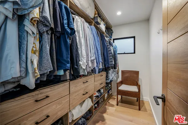 a view of walk in closet with clothes and shoes