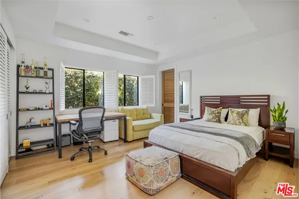 a bedroom with a bed and large windows