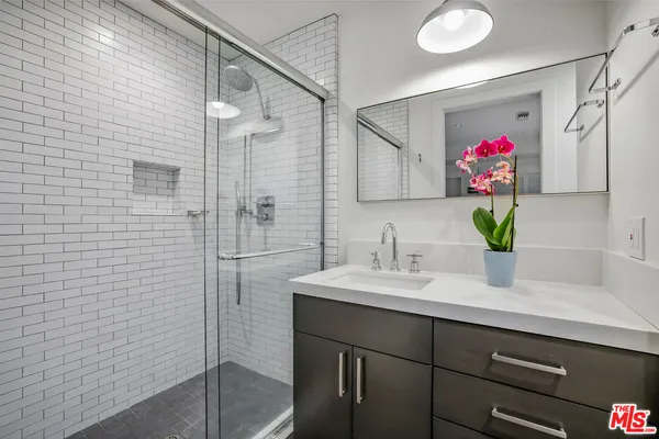 a bathroom with a sink vanity and a shower