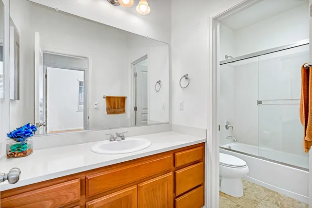 a bathroom with a granite countertop sink a toilet and shower