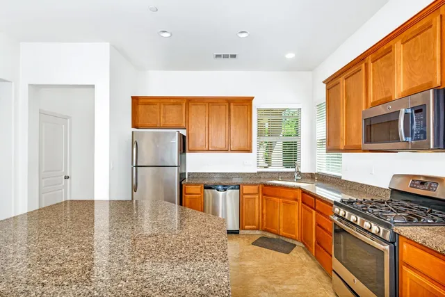 a kitchen with stainless steel appliances granite countertop a stove a sink and a refrigerator