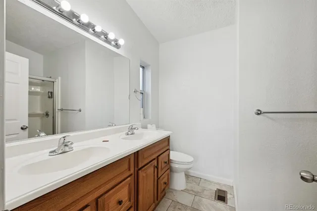 a bathroom with a double vanity sink a toilet and a mirror