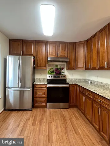 a kitchen with granite countertop wooden floors appliances and cabinets