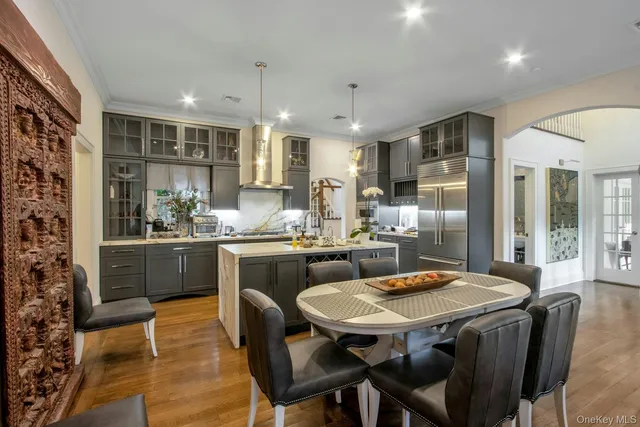 a kitchen with stainless steel appliances kitchen island granite countertop a table chairs sink and cabinets