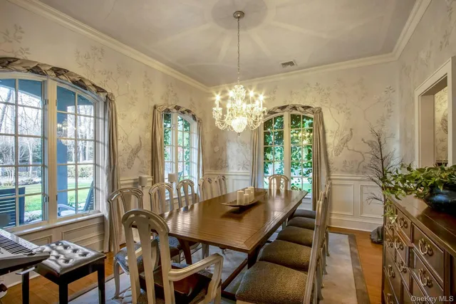 a view of a dining room with furniture a chandelier and large windows