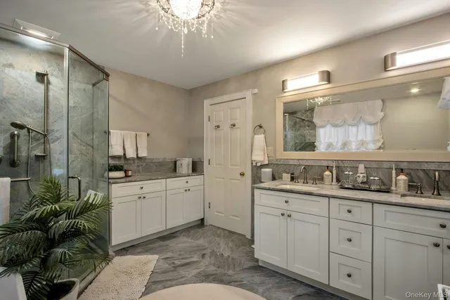 a spacious bathroom with a granite countertop sink a large mirror a shower and vanity