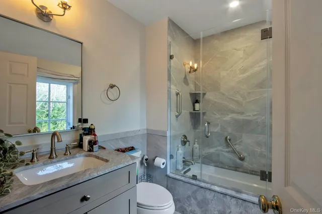a bathroom with a granite countertop sink toilet mirror and shower