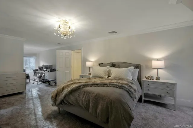 a spacious bedroom with a bed a chandelier and a couch