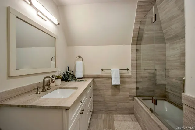 a bathroom with a granite countertop sink a mirror and shower