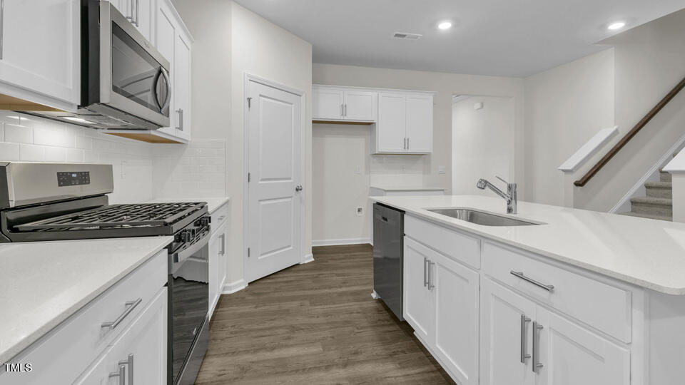 818 Comice Pear Way Willow Spring, NC 27592 - Photo 11 of 44 a kitchen with stainless steel appliances a sink dishwasher stove and white cabinets with wooden floor