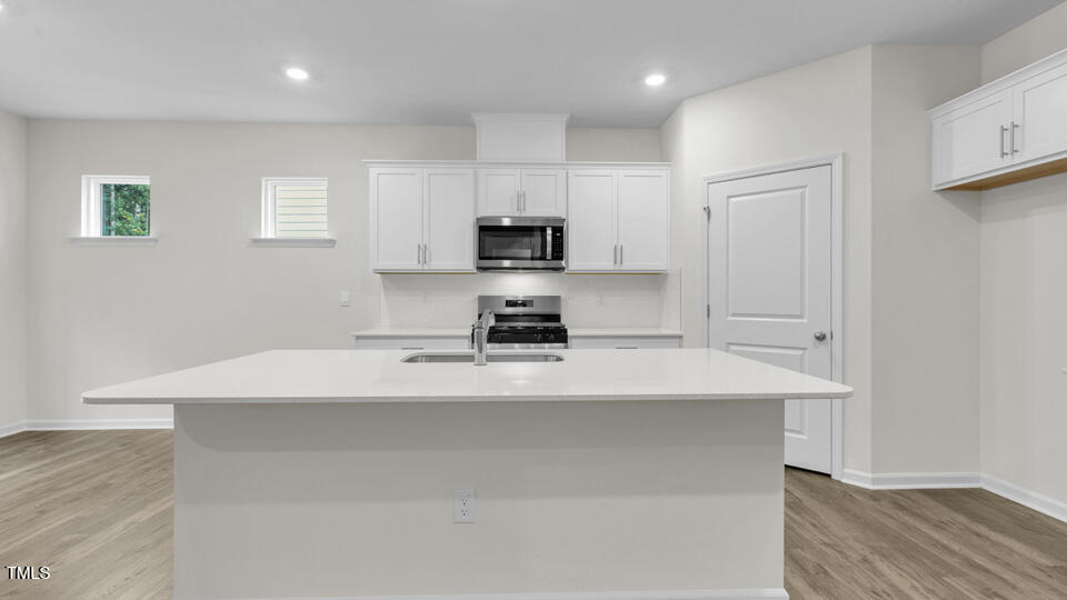 818 Comice Pear Way Willow Spring, NC 27592 - Photo 9 of 44 a kitchen with kitchen island a stove top oven a sink and white cabinets