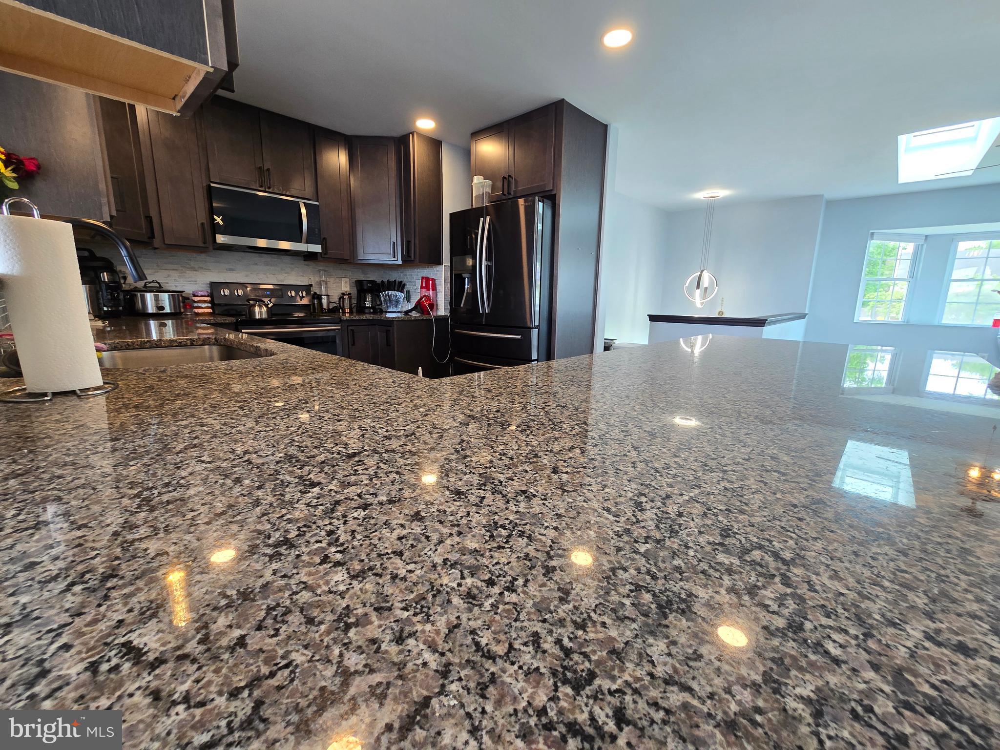 7513 Saffron Court Hanover, MD 21076 - Photo 10 of 42 a large kitchen with kitchen island granite countertop a large counter top stainless steel appliances and cabinets