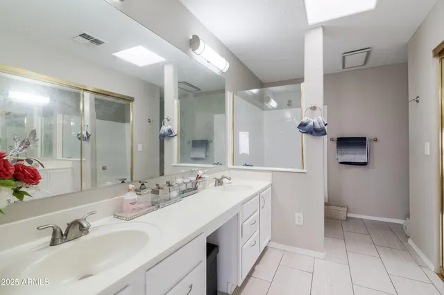 a spacious bathroom with a double vanity sink a mirror and a toilet