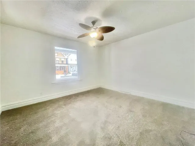 an empty room with windows and ceiling fan view