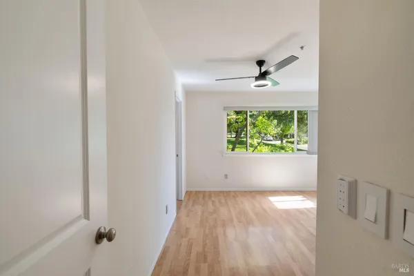 a view of empty room with wooden floor and fan