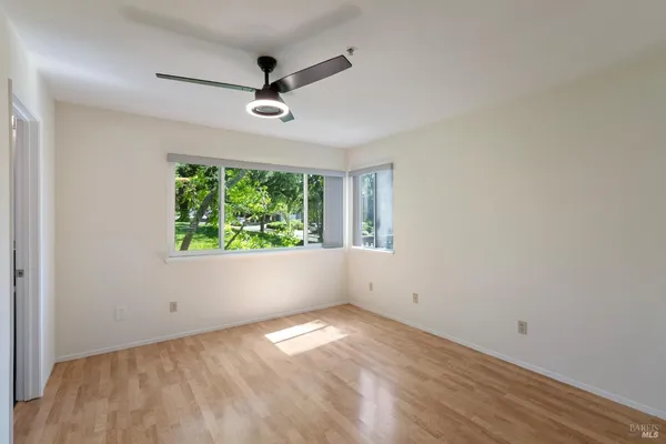 a view of empty room with wooden floor and fan