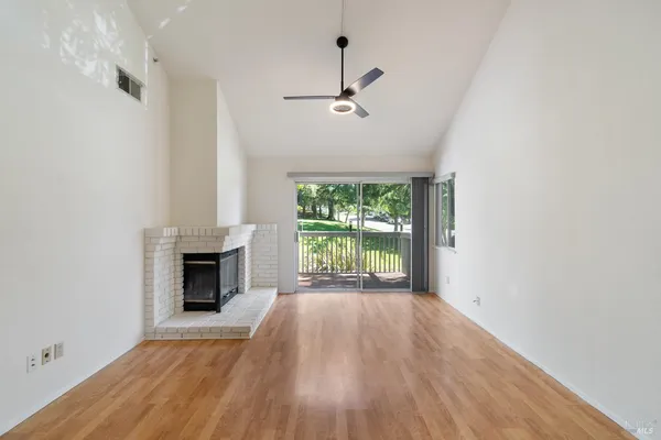 a view of empty room with wooden floor and fan