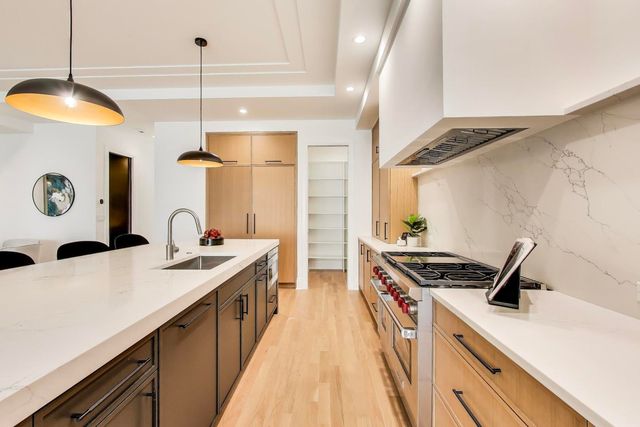 a large kitchen with a stove a sink a island and chairs