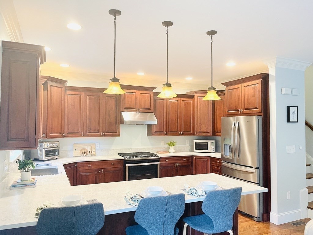 8 Cragmore Road, Unit 8 Newton, MA 02464 - Photo 9 of 27 a kitchen with stainless steel appliances a stove a sink a refrigerator a dining table and chairs