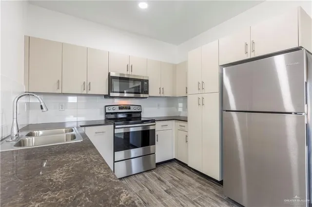 a kitchen with stainless steel appliances granite countertop a refrigerator stove a sink and a microwave