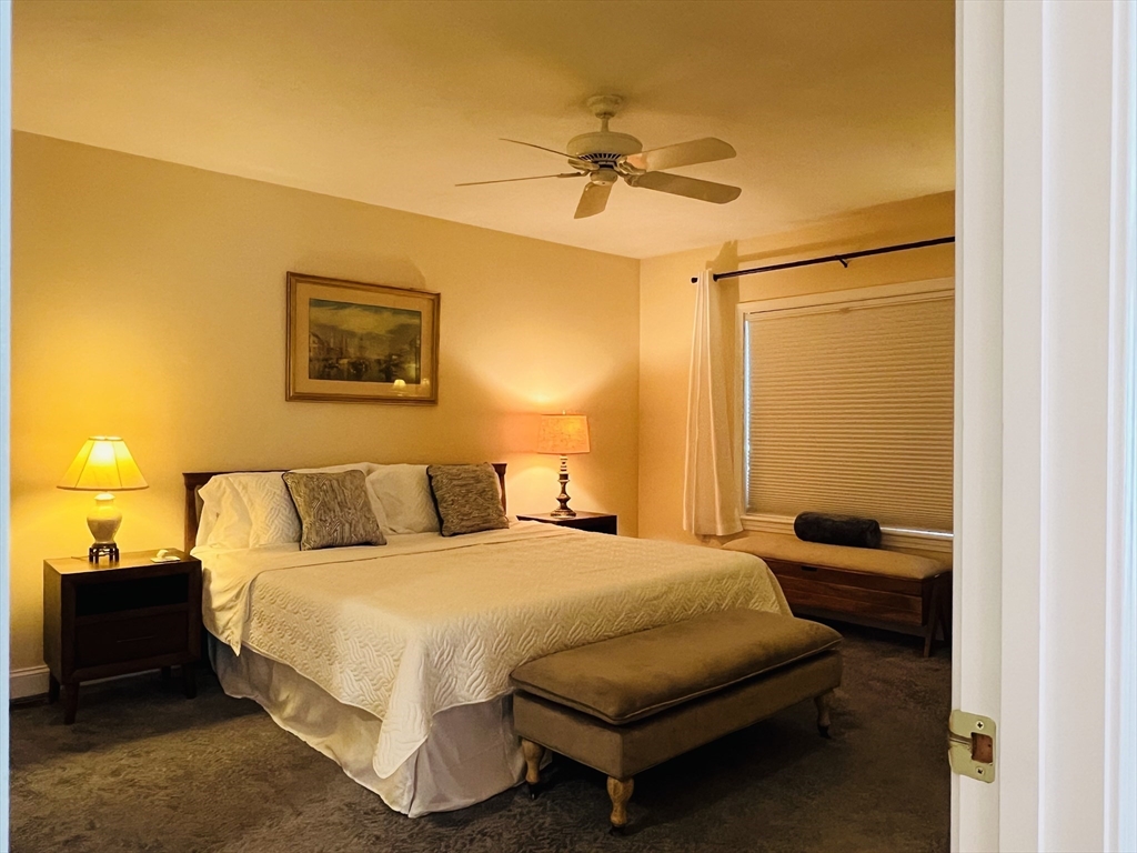 619 White Cliffs Drive, Unit 619 Plymouth, MA 02360 - Photo 29 of 42 a bedroom with a bed and a chandelier