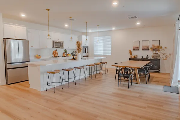 a kitchen with stainless steel appliances kitchen island granite countertop a dining table chairs and sink