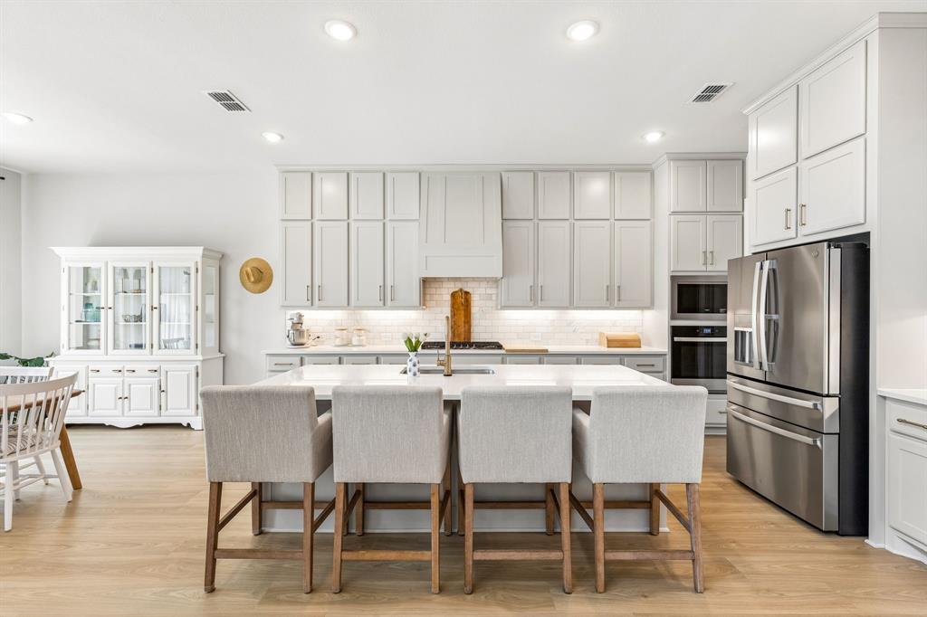 3004 Windy Rdg Road McKinney, TX 75071 - Photo 2 of 40 a kitchen with stainless steel appliances kitchen island granite countertop a dining table chairs refrigerator and sink