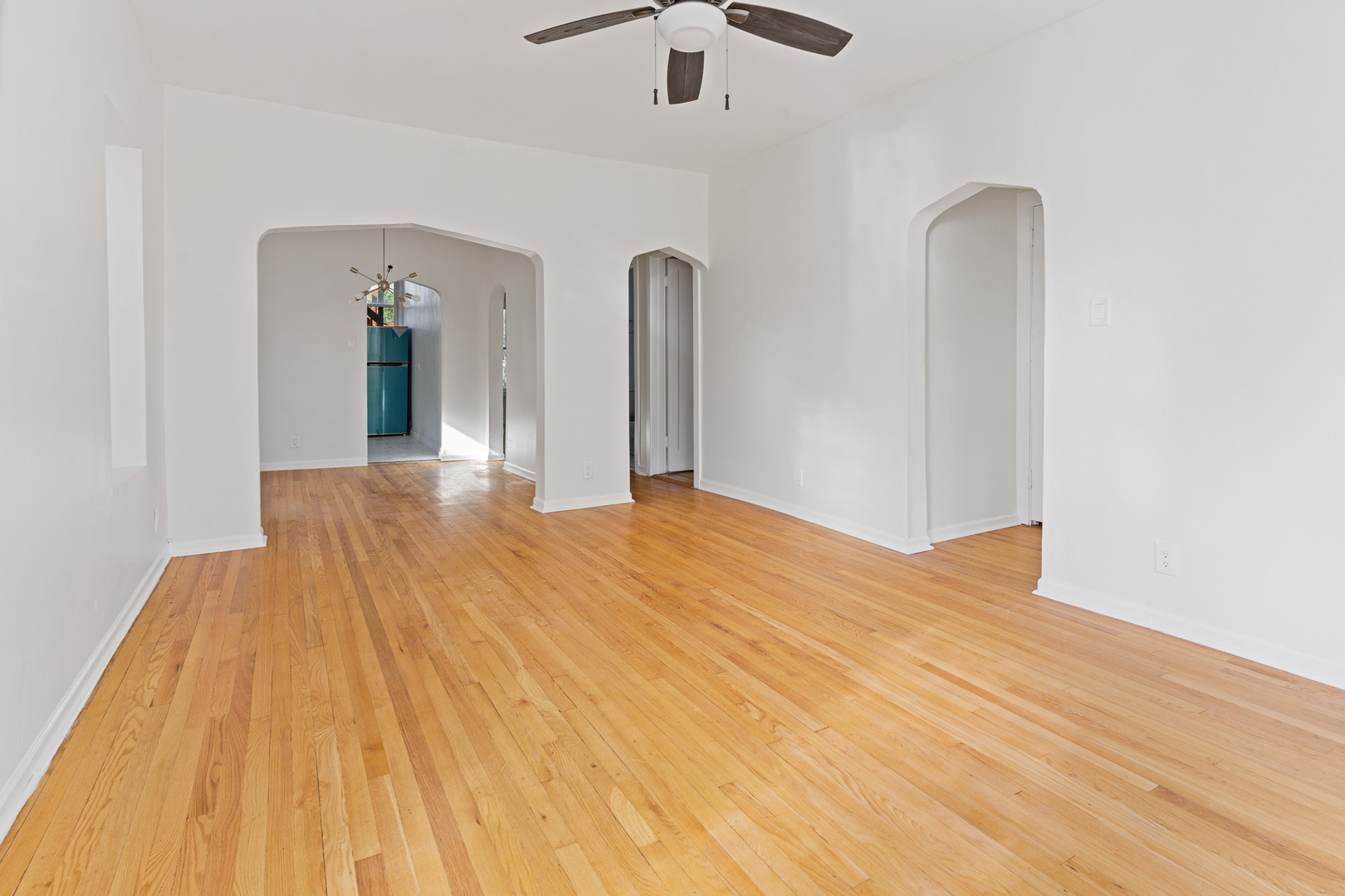 10342 South Calumet Avenue, Unit 3 Chicago, IL 60628 - Photo 20 of 25 a view of a room with wooden floor ceiling fan and kitchen view