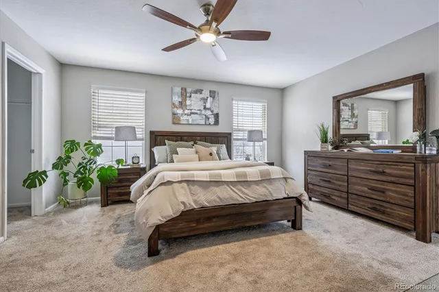 a bed sitting in a spacious bedroom next to a window and a chandelier